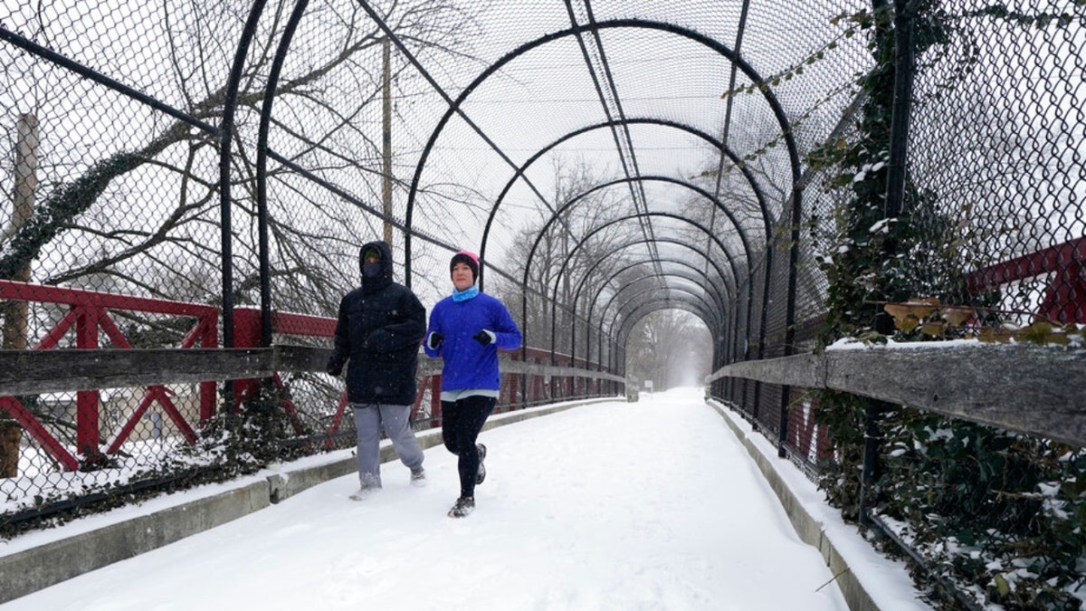 Biegacze biegną po pokrytej śniegiem trasie Monon Trial, czwartek, 3 lutego 2022 r. w Indianapolis. Potężna zimowa burza, którą napotykają miliony Amerykanów, sieje w całym kraju deszcz, marznący deszcz i obfite opady śniegu. (AP Photo/Darron Cummings) 