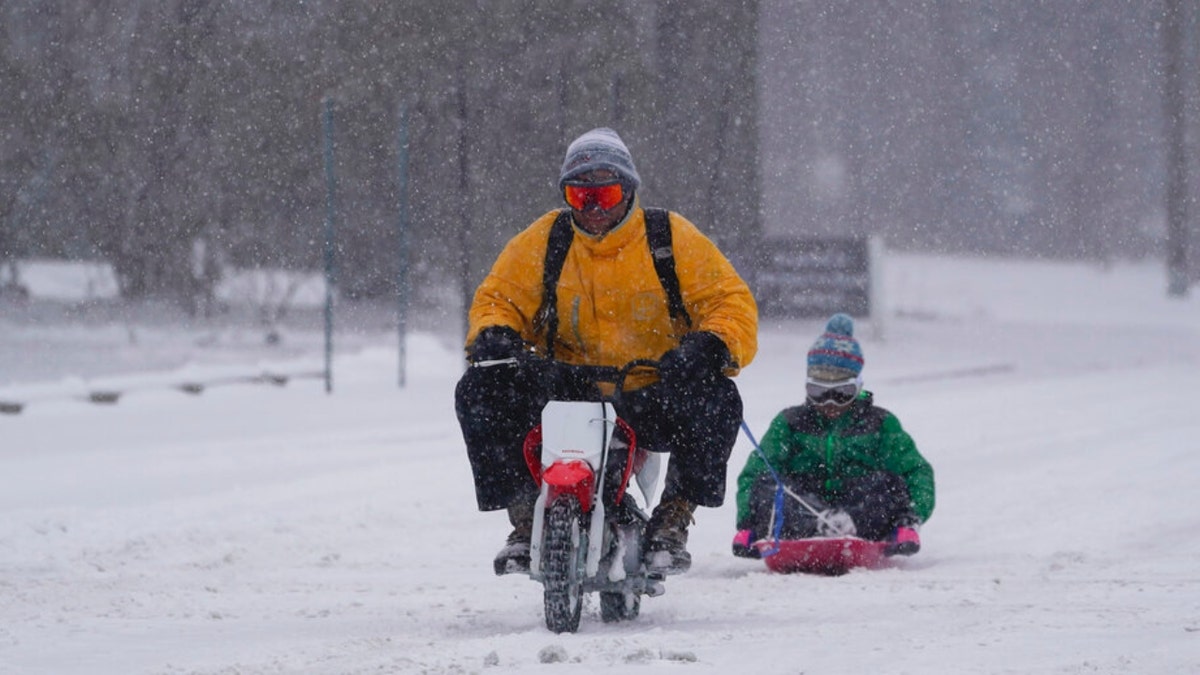 Adam Basch pulls Lim Walthall on his sled, Thursday, Feb. 3, 2022, in Indianapolis. A major winter storm with millions of Americans in its path is spreading rain, freezing rain and heavy snow further across the country.