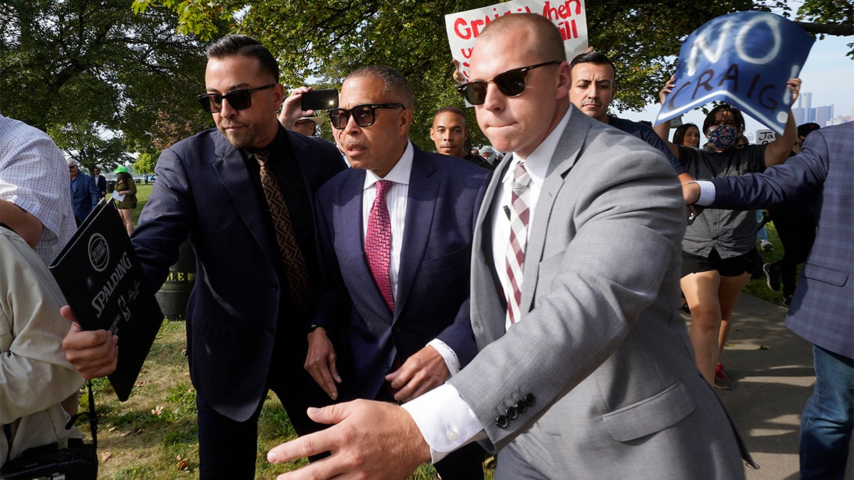 FILE - James Craig, center, a former Detroit Police chief, is escorted past protesters at a news conference on Belle Isle in Detroit, Tuesday, Sept. 14, 2021, where he announced he is a Republican candidate for governor of Michigan. 