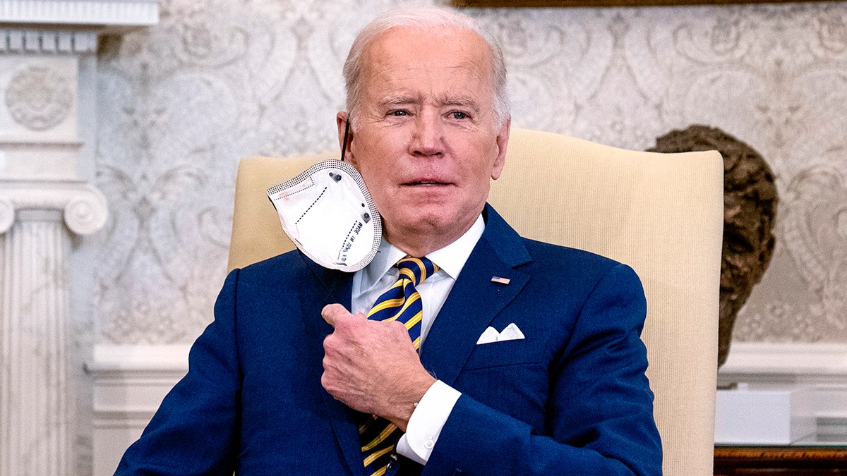 President Joe Biden removes his protective face mask before speaking during a meeting with the Qatar's Emir Sheikh Tamim bin Hamad Al Thani in the Oval Office of the White House, Monday, Jan. 31, 2022, in Washington. 