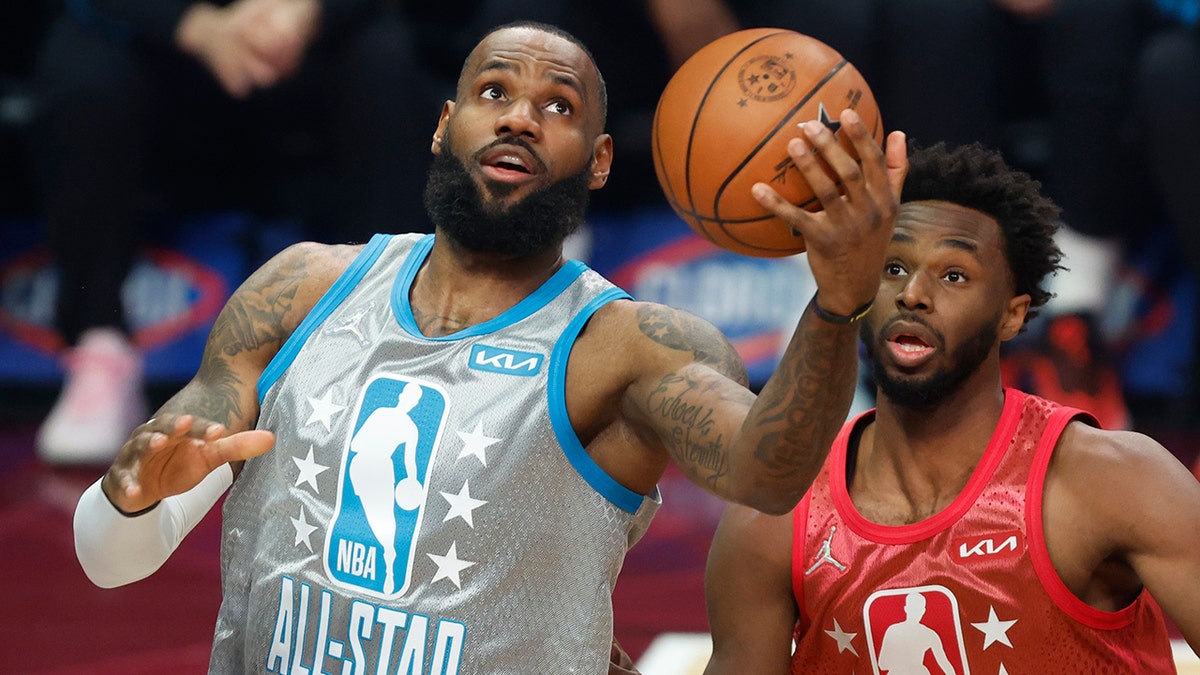 The Los Angeles Lakers' LeBron James, left, puts up a shot in front of the Golden State Warriors' Andrew Wiggins during the first half of the NBA All-Star basketball game, Sunday, Feb. 20, 2022, in Cleveland.