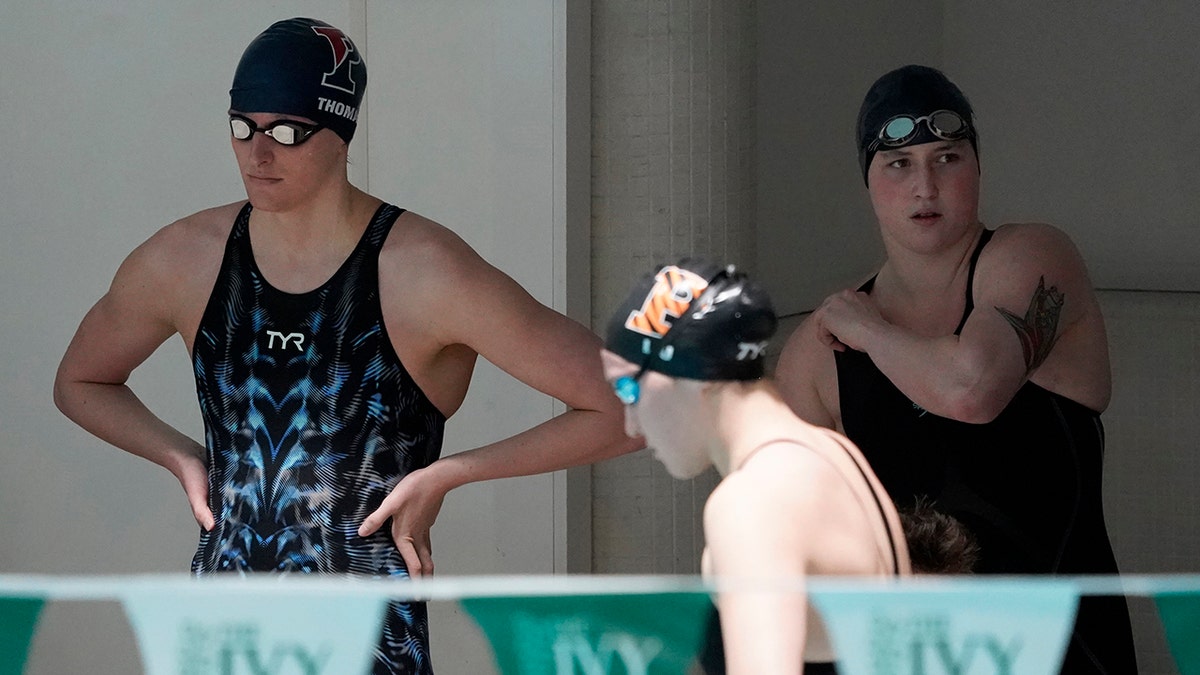 Penn's Lia Thomas, left, and Yale's Iszac Henig, right, prepare to swim in separate qualifying heats of the 100-yard freestyle at the Ivy League Women's Swimming and Diving Championships at Harvard University, Saturday, Feb. 19, 2022, in Cambridge, Mass.