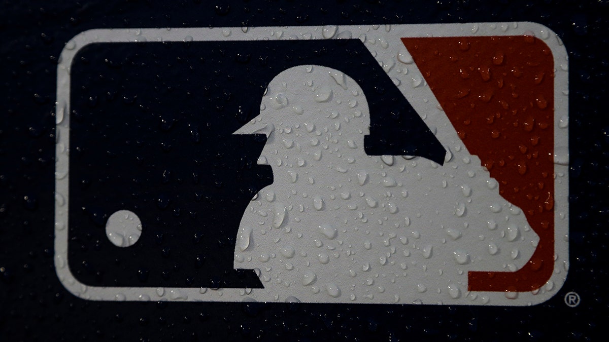 FILE - A rain-covered logo is seen at Fenway Park before Game 1 of the World Series baseball game between the Boston Red Sox and the Los Angeles Dodgers Tuesday, Oct. 23, 2018, in Boston. The mood for Major League Baseball fans is a little glum these days as the players' union and owners continue to bicker over finances. The owners locked out the players on Dec. 2 and unless an agreement between the two sides is reached soon, the spring training schedule is in trouble. The first games are slated for Feb. 26, 2022.