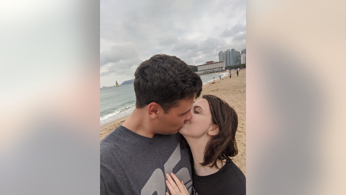 Forrest Severson and wife Sarah Arnold kiss at the beach.