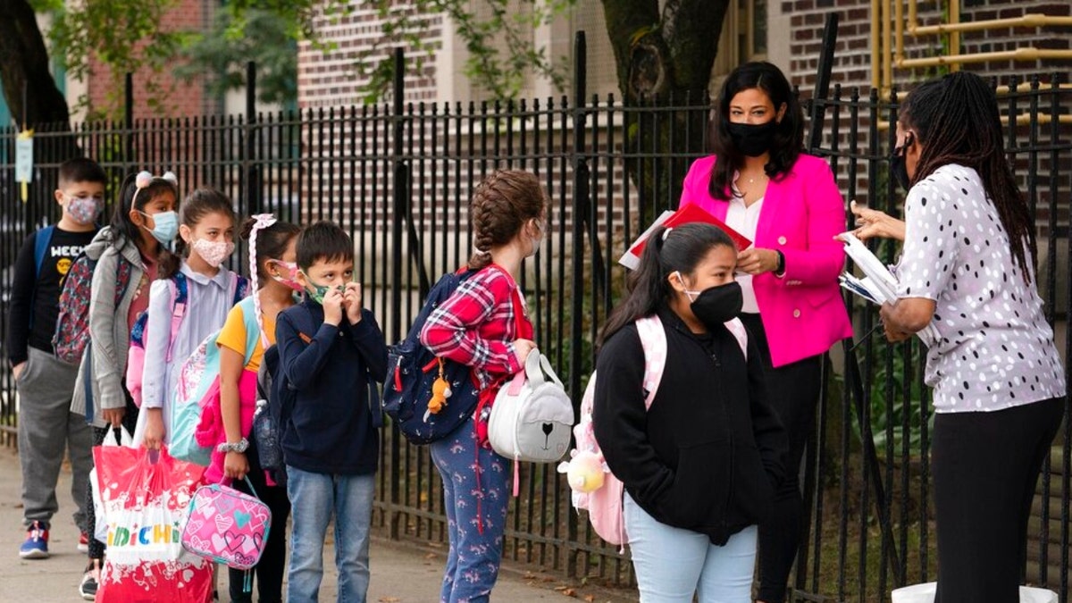 FILE — Teachers line up their students before entering PS 179 elementary school in the Kensington neighborhood, Sept. 29, 2020, in the Brooklyn borough of New York. New York City public school students will be allowed to remove their masks outside starting next week but must keep them on indoors for now. 