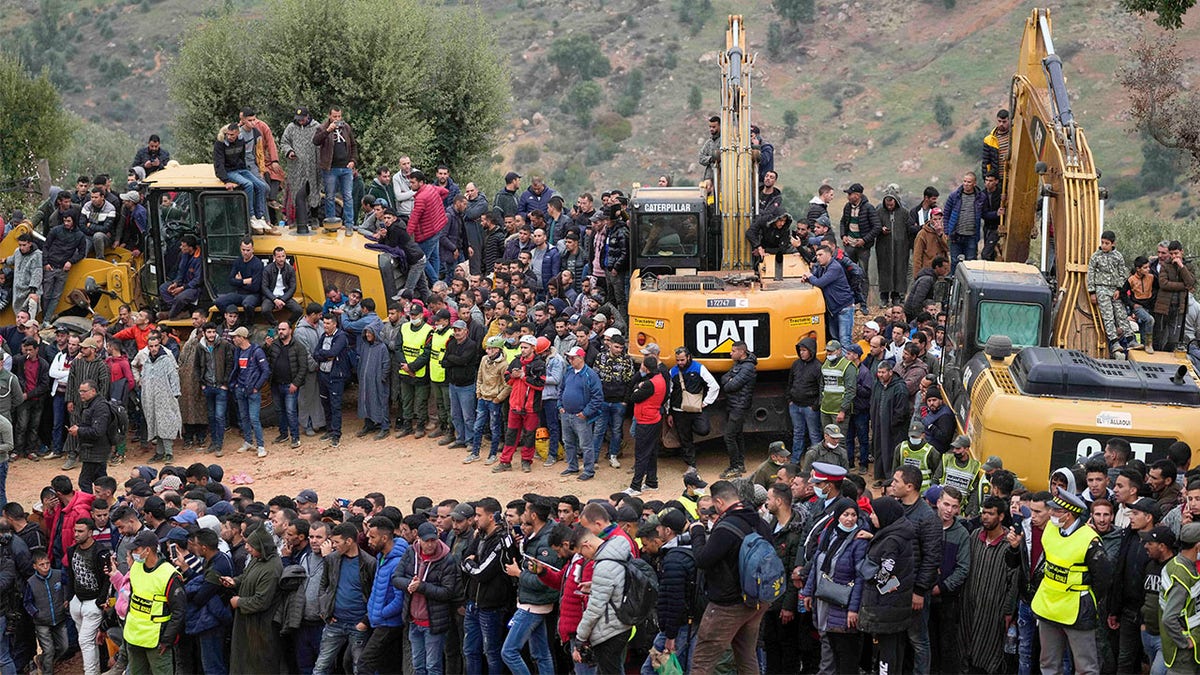 Residents stand on top of tractors as they watch civil defense workers and local authorities attempting to rescue a 5-year-old boy who fell into a hole in the northern village of Ighran 