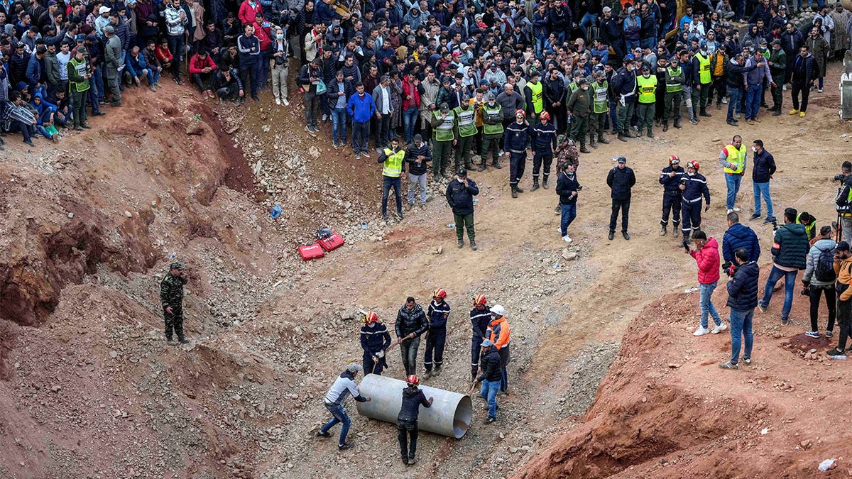 Rescue workers roll cylinders as they attempt to build a tunnel to rescue a 5-year-old boy who fell into a hole in the northern village of Ighran in Morocco's Chefchaouen province, Friday, Feb. 4, 2022. 