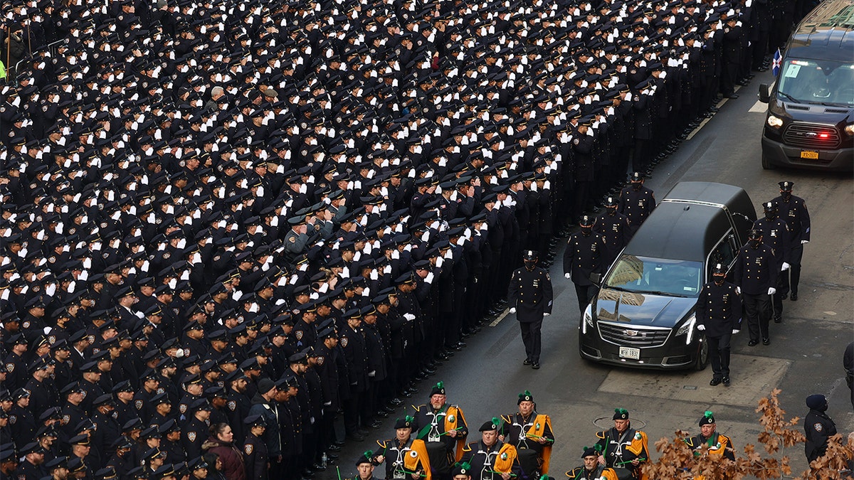 New York Police salute as a hearse carrying the casket of NYPD Officer Wilbert Mora is escorted down Fifth Avenue as it departs from St. Patrick's Cathedral after a funeral service for Mora, Wednesday, Feb. 2, 2022, in New York.