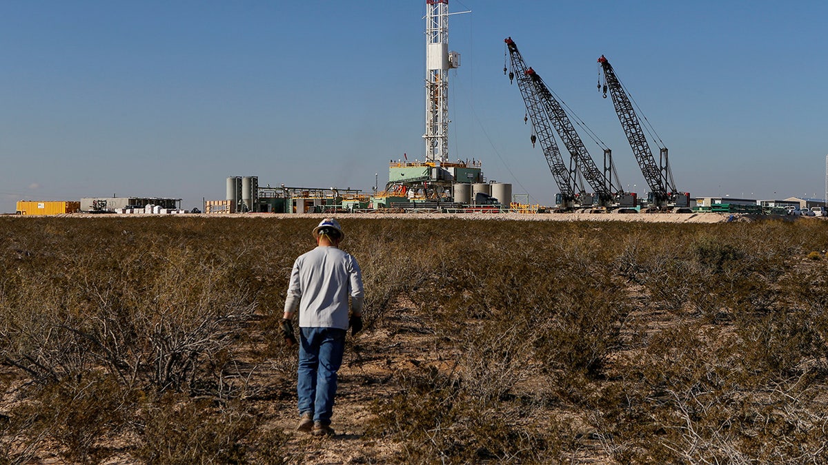 An oil worker walks toward a drill rig after placing ground monitoring equipment in the vicinity of the underground horizontal drill in Loving County, Texas, Nov. 22, 2019.