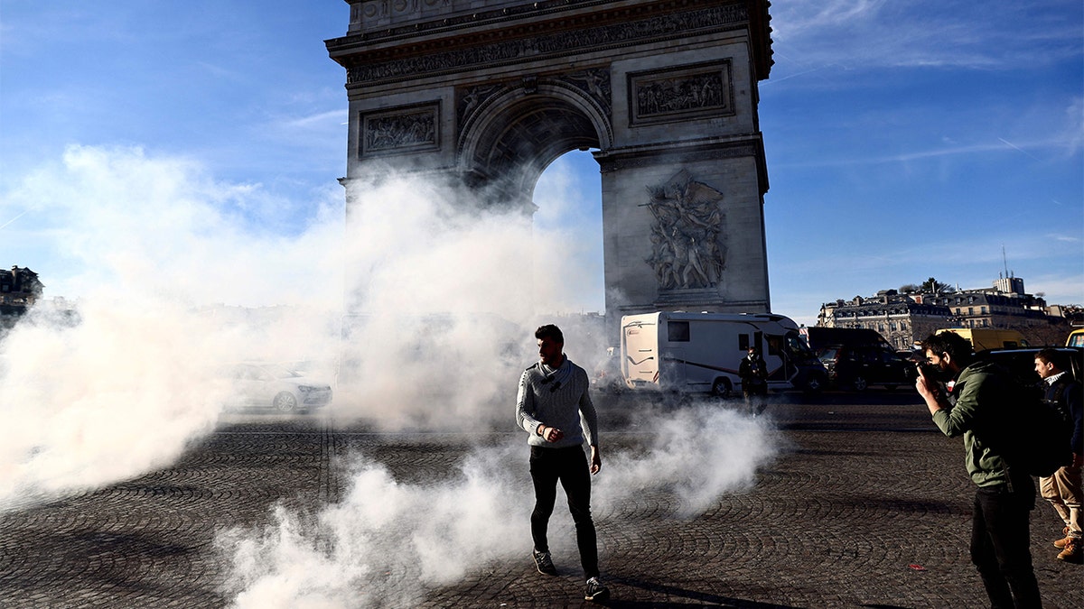 A man walks through tear gas on the Place Charles De Gaulle in Paris Feb. 12, 2022, as convoys of protesters, "Convoi de la Liberte," arrived in the French capital. 