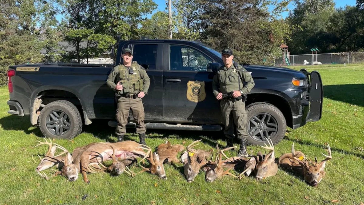 Conservation Officers Tyler Cole, left, and Matt Page with the heads of eight deer poached by Justin Ernst, 33, of Decatur, Michigan