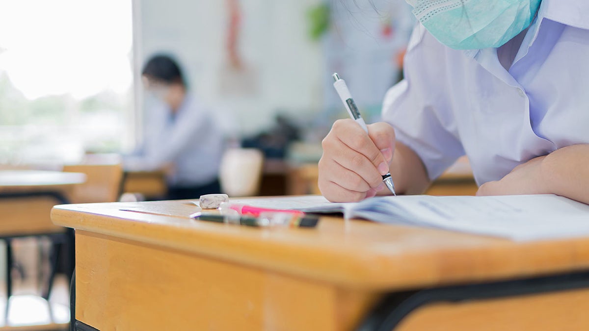 Student writing on paper at desk