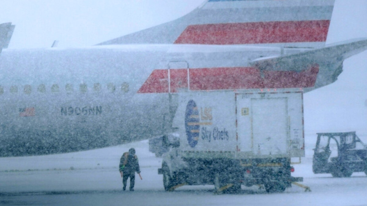 Snow falls on a ground crew working outside a parked plane at Dallas Fort Worth International Airport in Grapevine, Texas, Thursday, Feb. 3, 2022. The historic freeze covered the Lone Star State and left millions without power. (AP Photo/LM Otero)