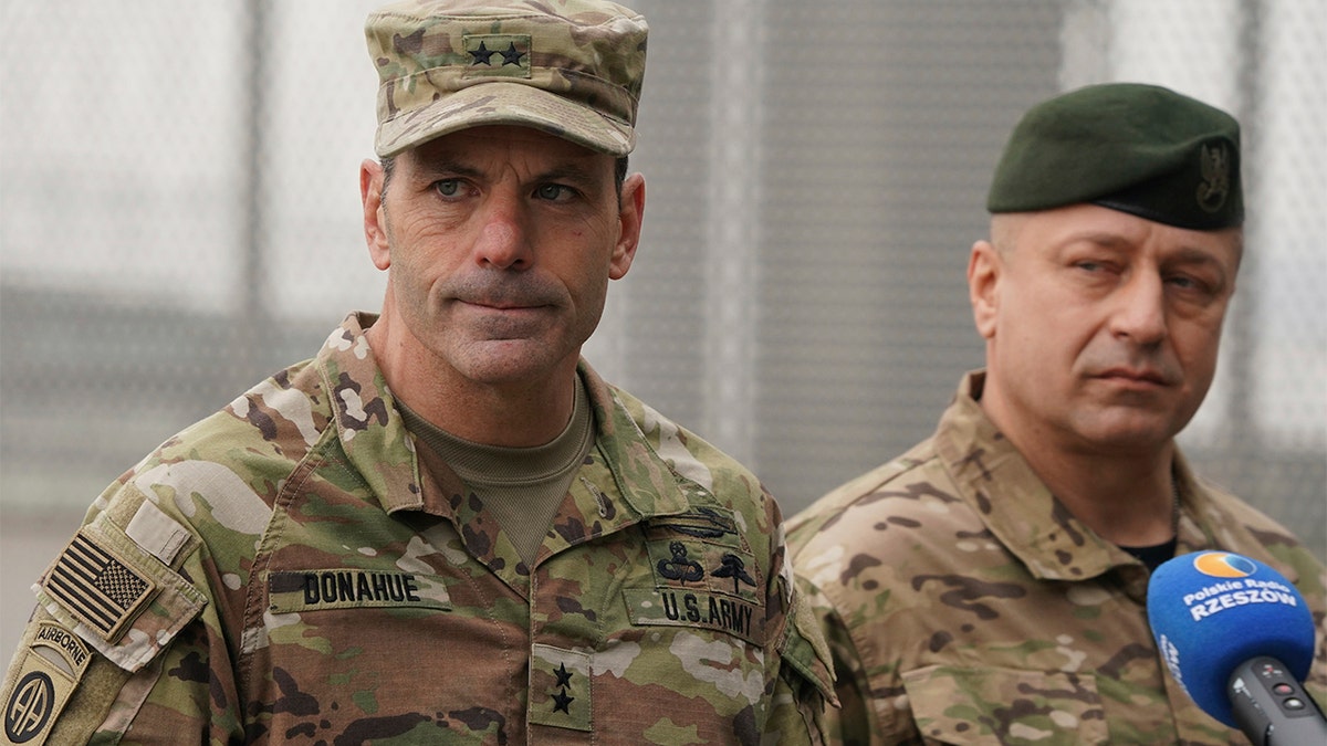 US Army General Christopher Donahue, left, commanding general of the 82nd Airborne Division, and Polish General Wojciech Marchwica speak to journalists after unloading vehicles from a transport plane arriving from Fort Bragg at the Rzeszow-Jasionka airport in southeastern Poland, on Sunday, Feb. 6, 2022.