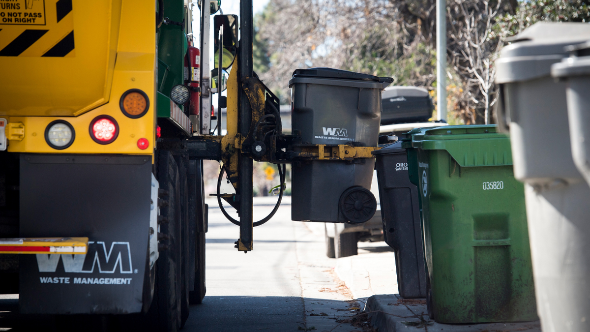 A Waste Management Inc. garbage collection truck empties a trash bin outside a home in Hayward, California, U.S., on Monday, Feb. 12, 2018