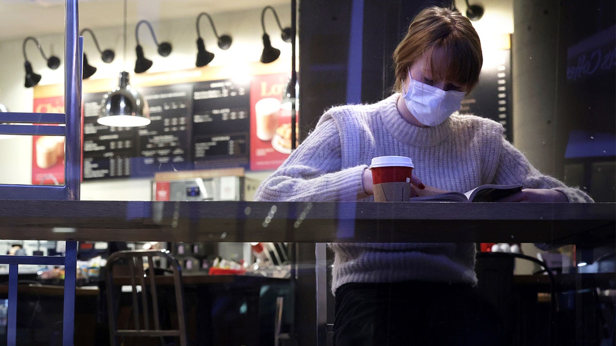 Tourist Elizabeth Senter wears a mask as she reads her book at a coffee shop Dec. 21, 2021, in Washington, DC.