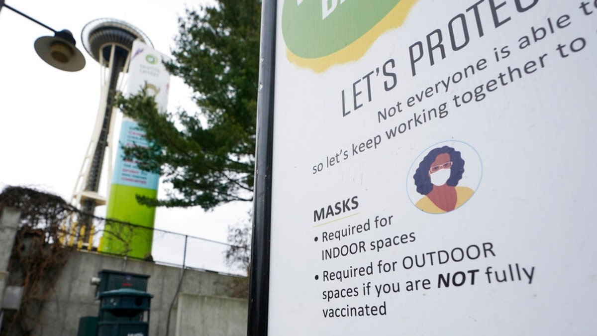 A sign near the Space Needle notes that masks are required for indoor spaces, Thursday, Feb. 17, 2022, in Seattle. (AP Photo/Ted S. Warren)