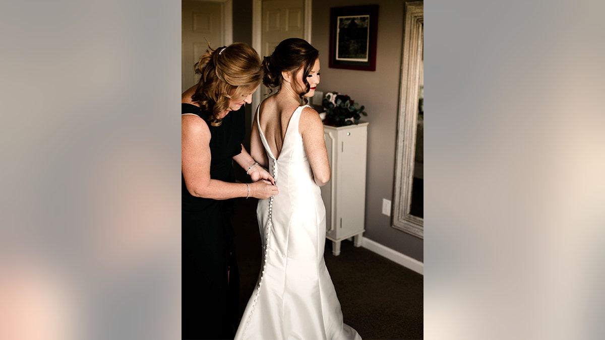 Mother and daughter attend to the bride's beautiful wedding dress. Before this happy time, there was drama, upset — and a medical emergency.