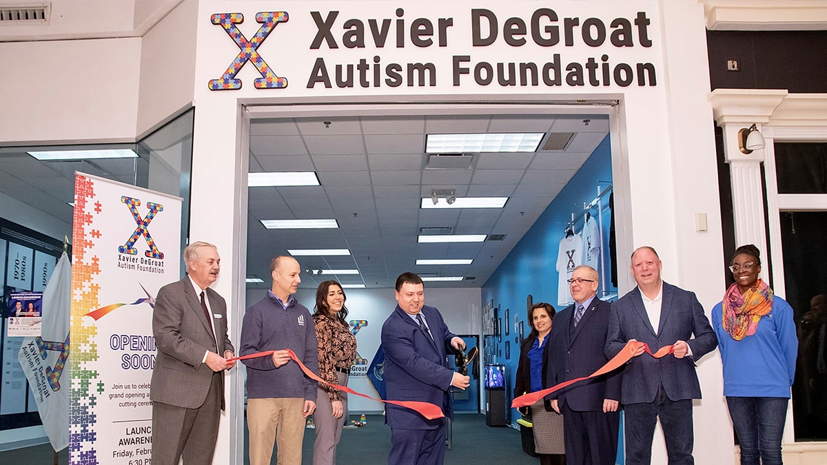 Xavier DeGroat, center, at the ribbon cutting ceremony for his Autism History Museum  at the Meridian Mall in Okemos, Mich, on Feb. 4, 2022.