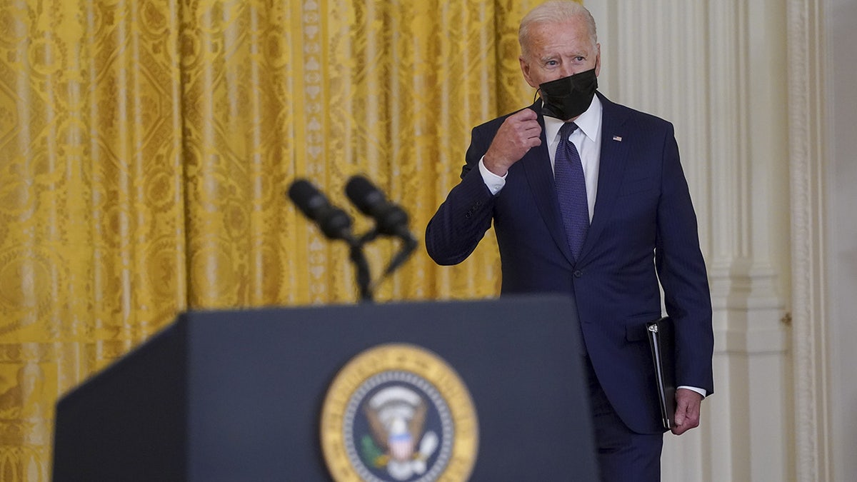 President Biden removes his protective mask while arriving to speak in the East Room of the White House in Washington, D.C., U.S., on Thursday, Aug. 26, 2021. 