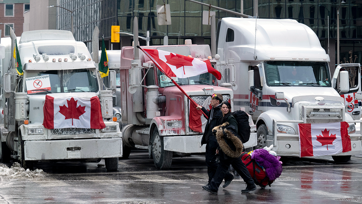 Protesters walk with bags past trucks parked on downtown streets on Wednesday, Feb. 2, 2022, in Ottawa, Ontario.