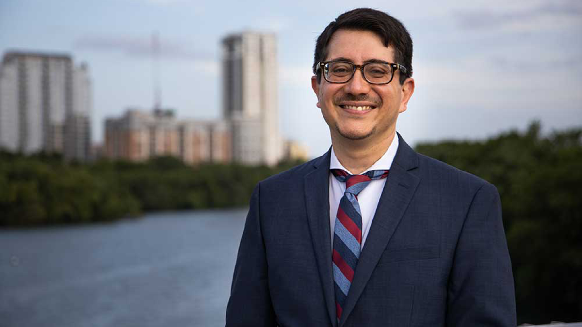 Jose Garza wearing a suit smiling in front of Austin skyline