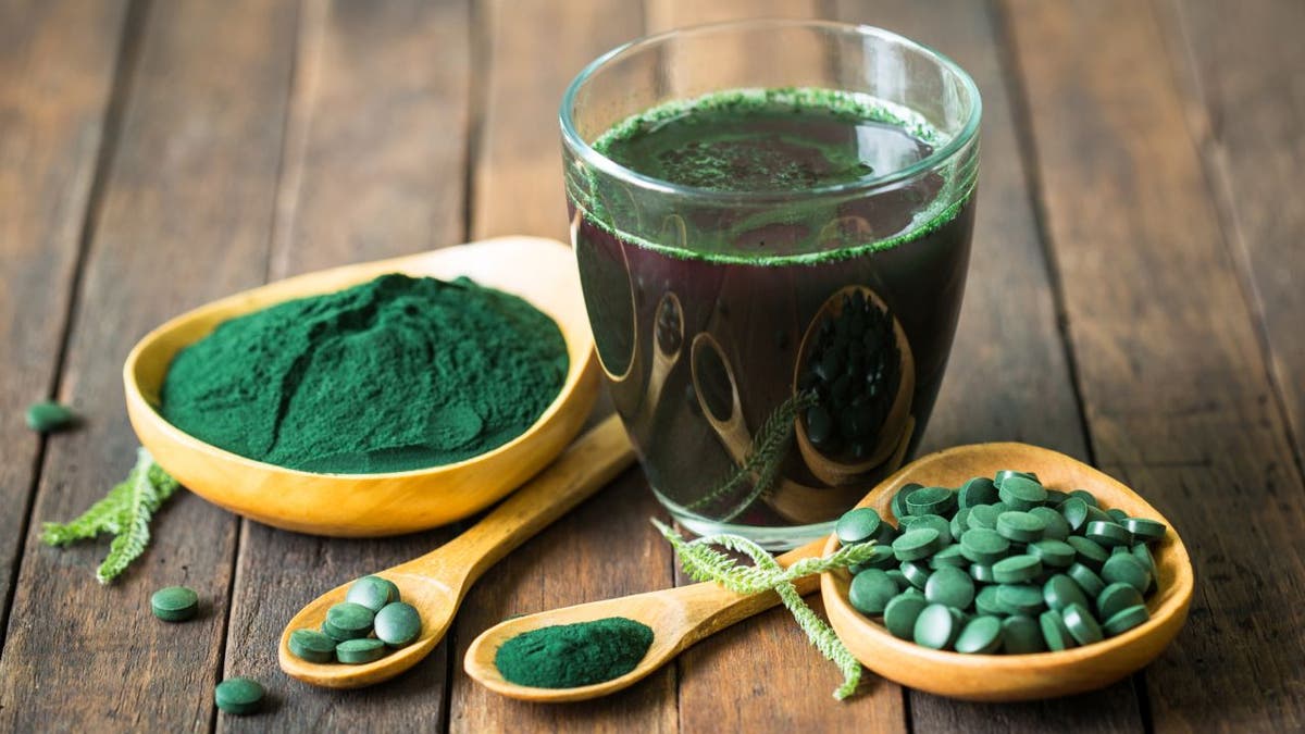 Spirulina in cup, spoon, small bowls and tablets