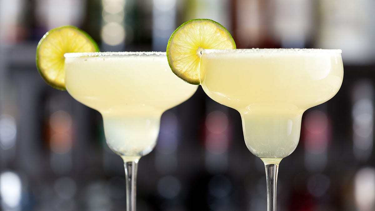 Two margaritas with lime wedges and salted glasses