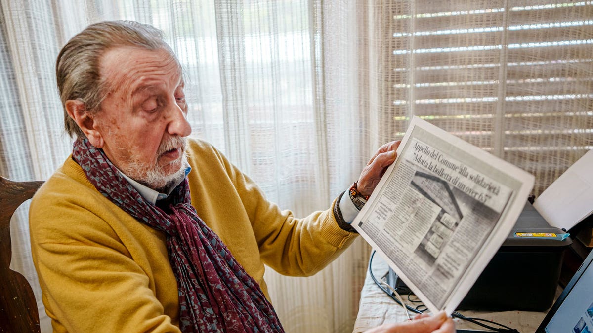 Luigi Boni, a 95-year-old Florentine retiree, shows a newspaper article about the 