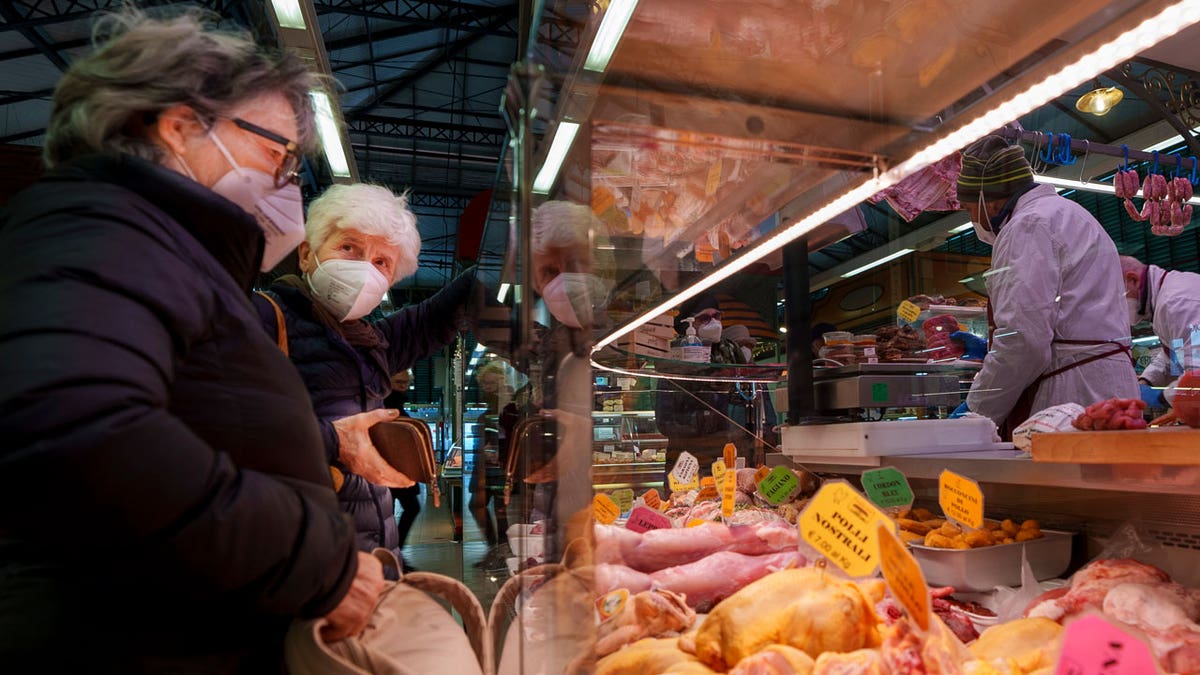 Two elderly women buy food in a market in Florence, Italy, Thursday, Feb. 17, 2022. 