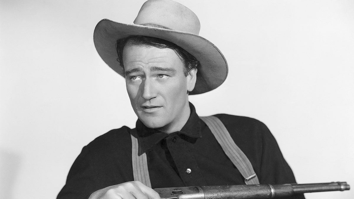 John Wayne holding a rifle in a publicity photo for the movie "Shepherd of the Hills."