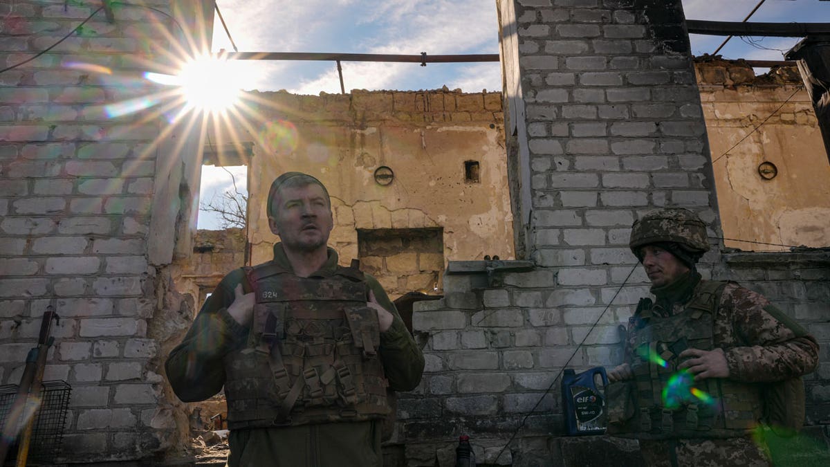 Ukrainian servicemen stand by a destroyed house near the frontline village of Krymske, Luhansk region, in eastern Ukraine, Saturday, Feb. 19, 2022.