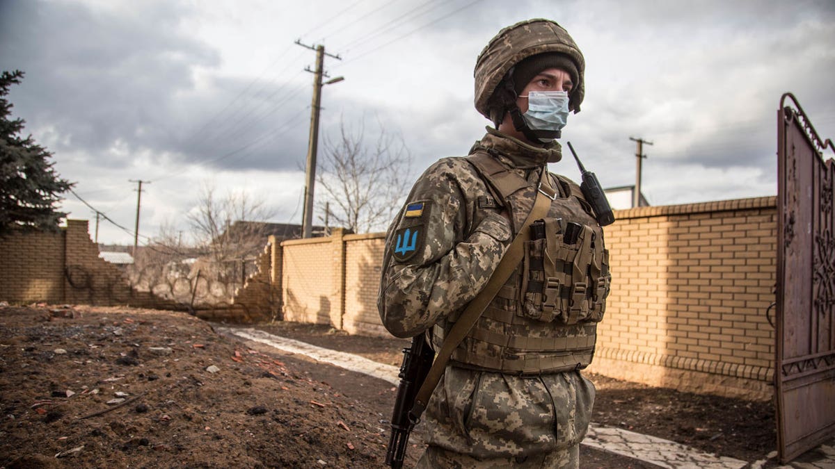 A Ukrainian soldier passes by houses in the village of Novoluhanske, Luhansk region, Ukraine, Saturday, Feb. 19, 2022.