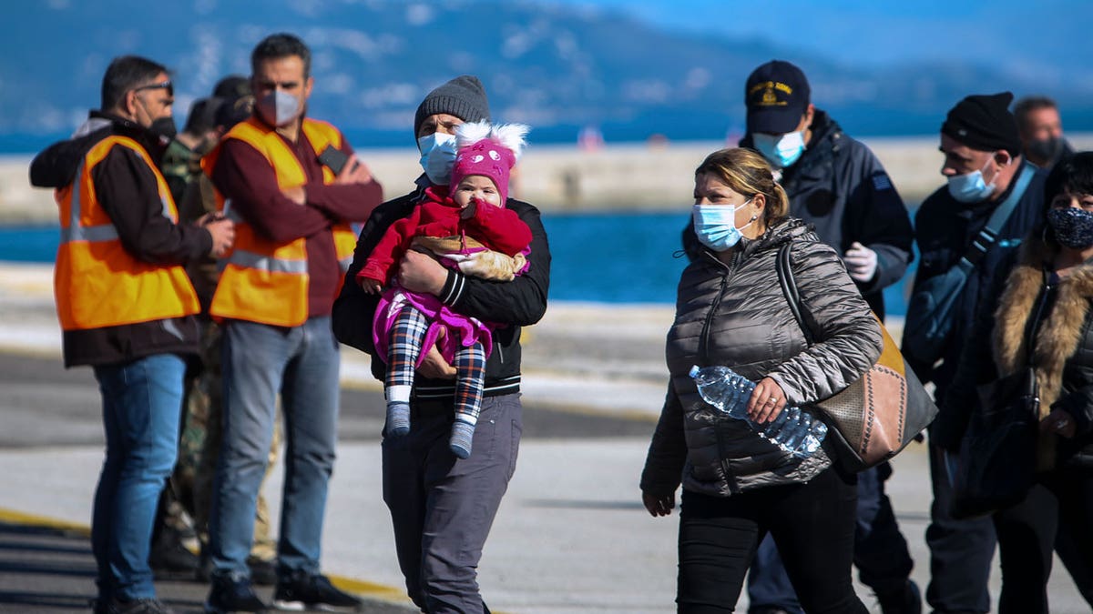 Passengers arrive at the port of Corfu island, northwestern Greece, after being evacuated from a ferry, Friday, Feb. 18, 2022. More than 280 people have been evacuated from a ferry in northwestern Greece that caught fire overnight while heading to southern Italy, authorities said.