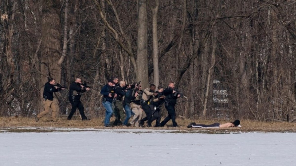 Police approach a suspect on the south bank of the North River in Bridgewater, Va. following a shooting at Bridgewater College Tuesday, Feb. 1, 2022. 