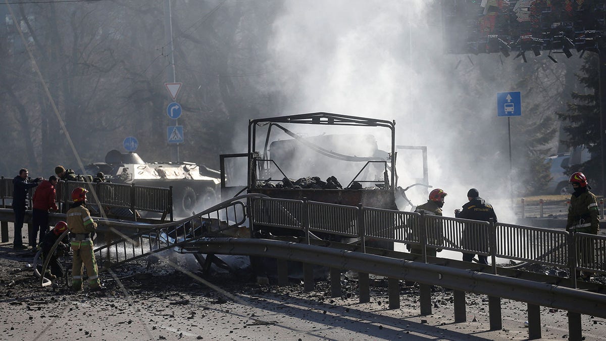 Ukrainian servicemen and first responders stand by a damaged vehicle, at the site of fighting with Russian troops, after Russia launched a massive military operation against Ukraine, in Kyiv, Ukraine February 26, 2022. 