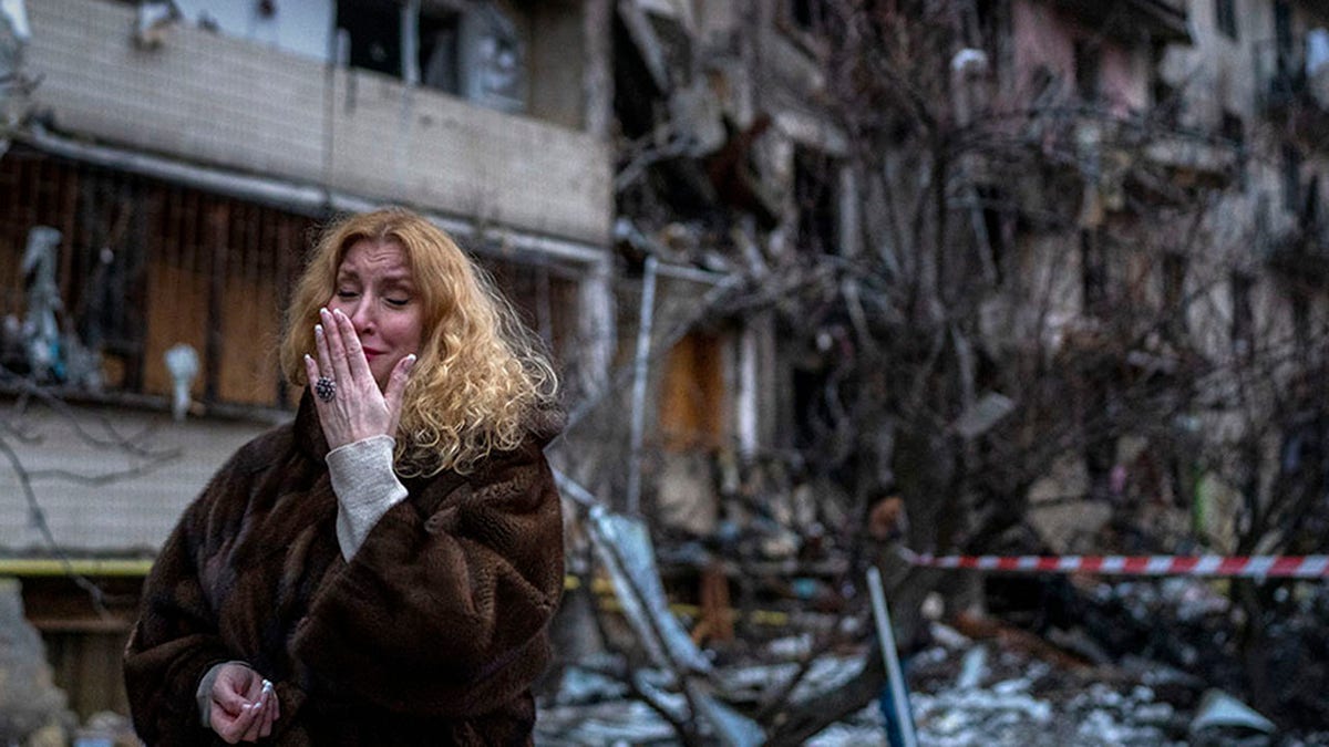 Natali Sevriukova reacts next to her house following a rocket attack the city of Kyiv, Ukraine, Friday, Feb. 25, 2022. 