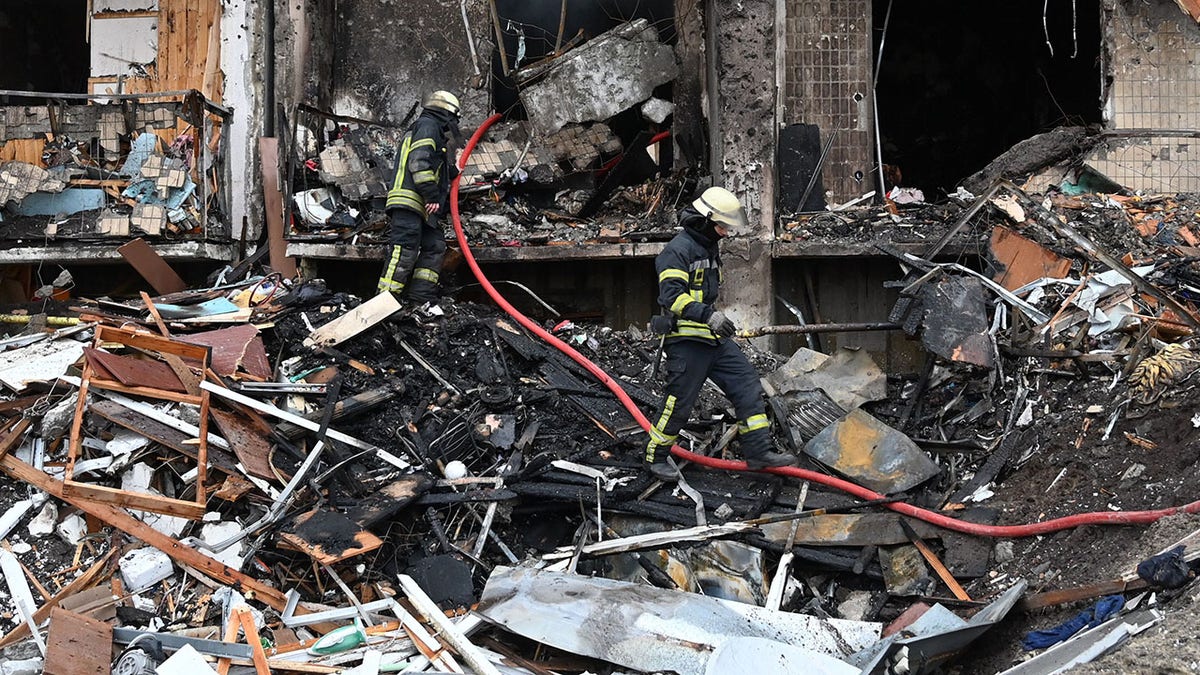 Firefighters work at a damaged residential building at Koshytsa Street, a suburb of the Ukrainian capital Kyiv, where a military shell allegedly hit, on Feb. 25, 2022. 