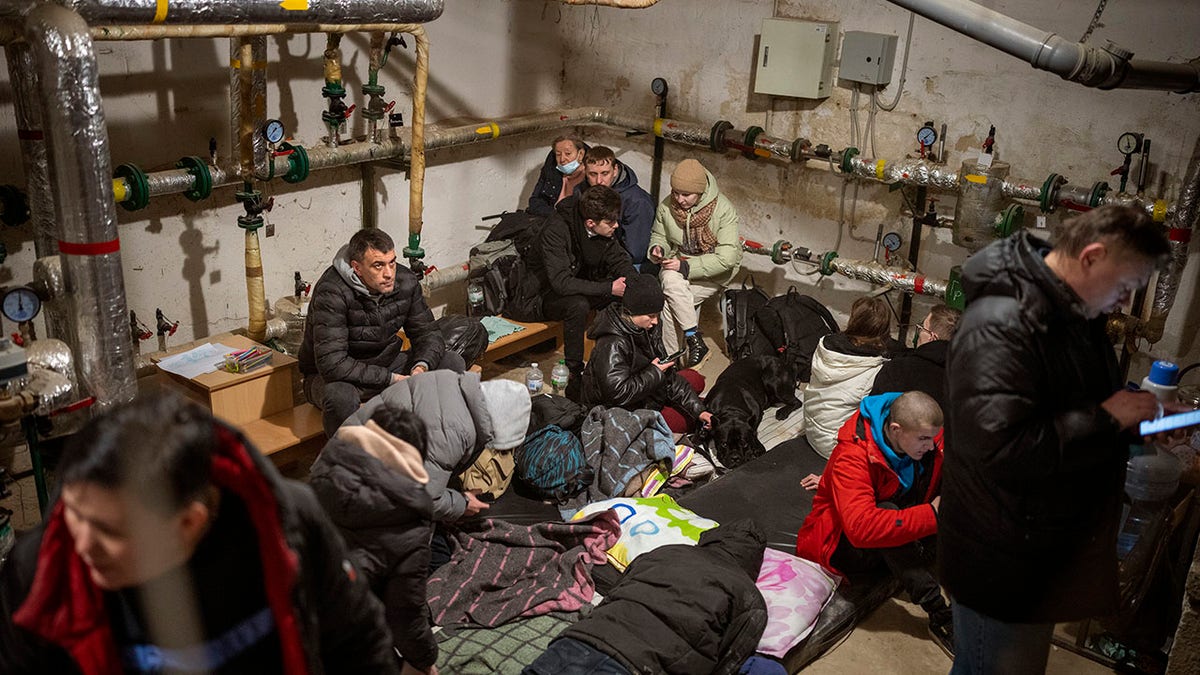 People take shelter at a building basement while the sirens sound announcing new attacks in the city of Kyiv, Ukraine, Friday, Feb. 25, 2022.