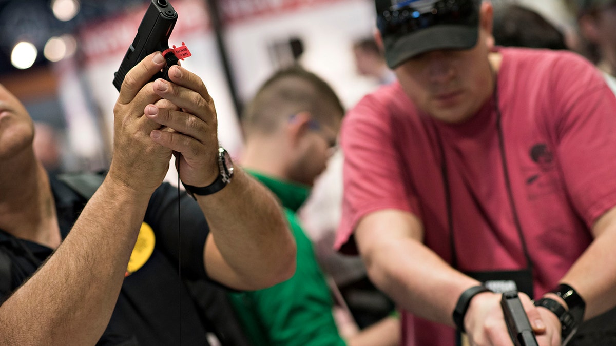 Attendees look over Glock, Inc. pistols on the exhibition floor of the 144th National Rifle Association (NRA) Annual Meetings and Exhibits at the Music City Center in Nashville, Tennessee, April 11, 2015.