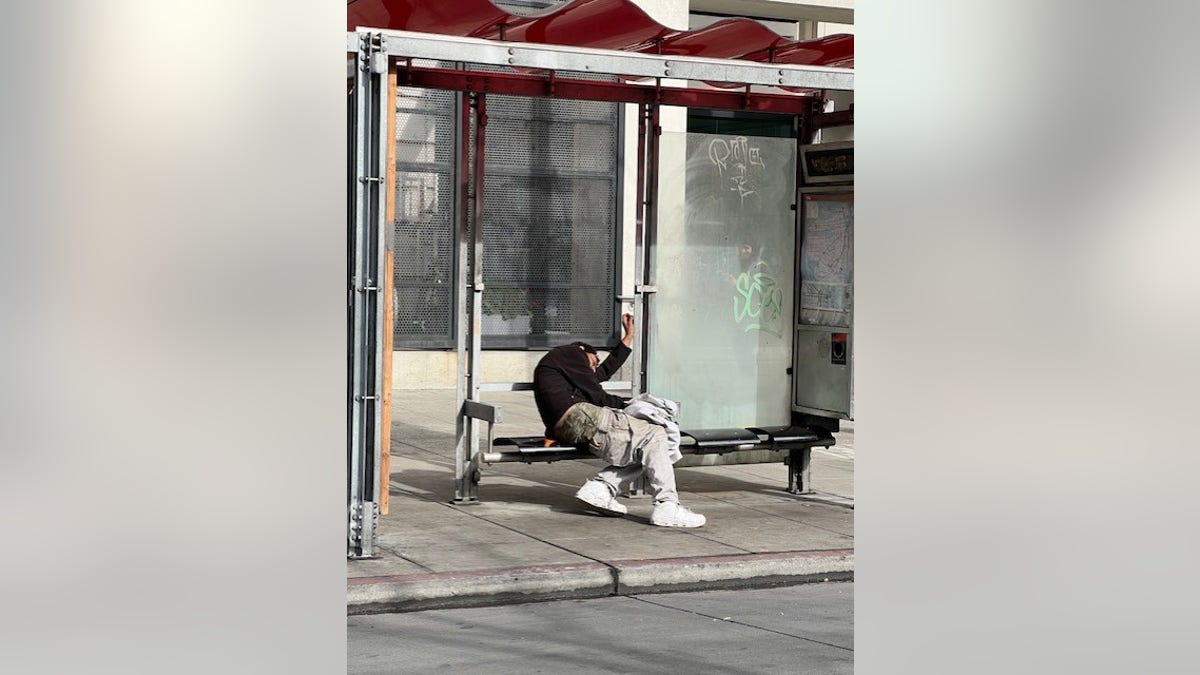 A homeless man sits at a San Francisco bus shelter in the Tenderloin District 