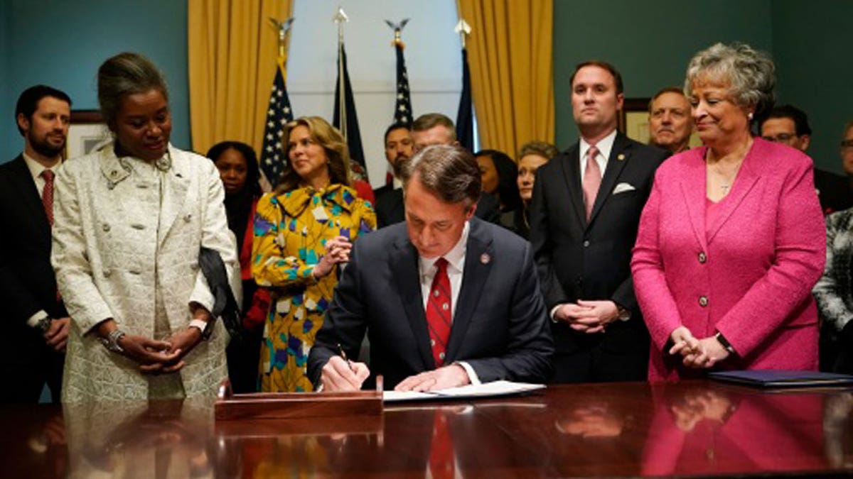 Virginia Gov. Glenn Youngkin, center, signs executive orders in the Governor's conference room as Lt. Gov. Winsome Earle-Sears, left, Suzanne Youngkin, second from left, Attorney General Jason Miyares, second from right, and Secretary of the Commonwealth, Kay Cole James, right, look on at the Capitol Saturday Jan. 15, 2022, in Richmond, Virginia. 