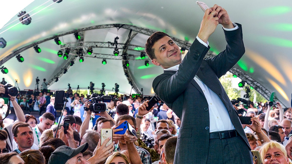 Ukrainian President Volodymyr Zelenskyy takes a selfie at the first congress of his party called Servant of the People in the city Botanical Garden, Kiev, Ukraine, Sunday, June 9, 2019.