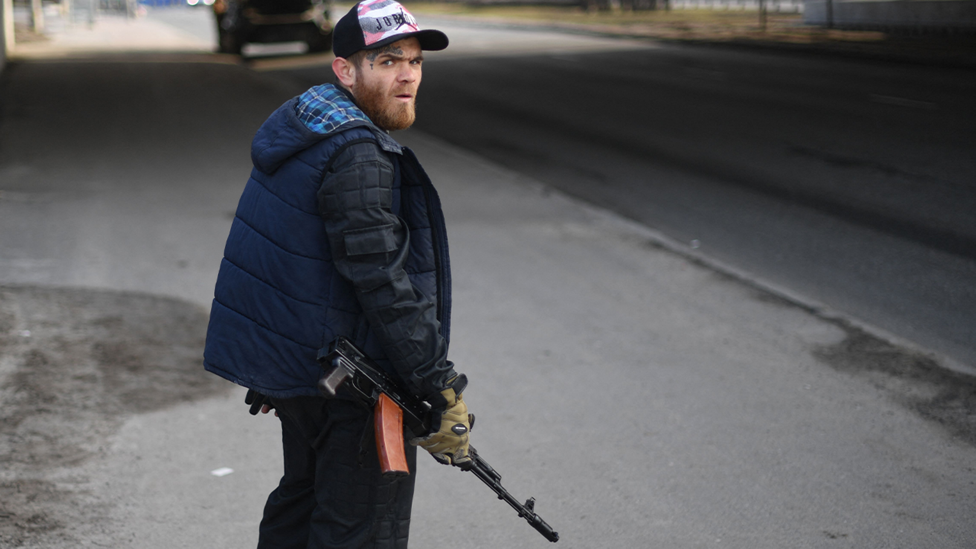 A volunteer, holding a rifle, protects a main road leading into Kyiv on February 25, 2022.