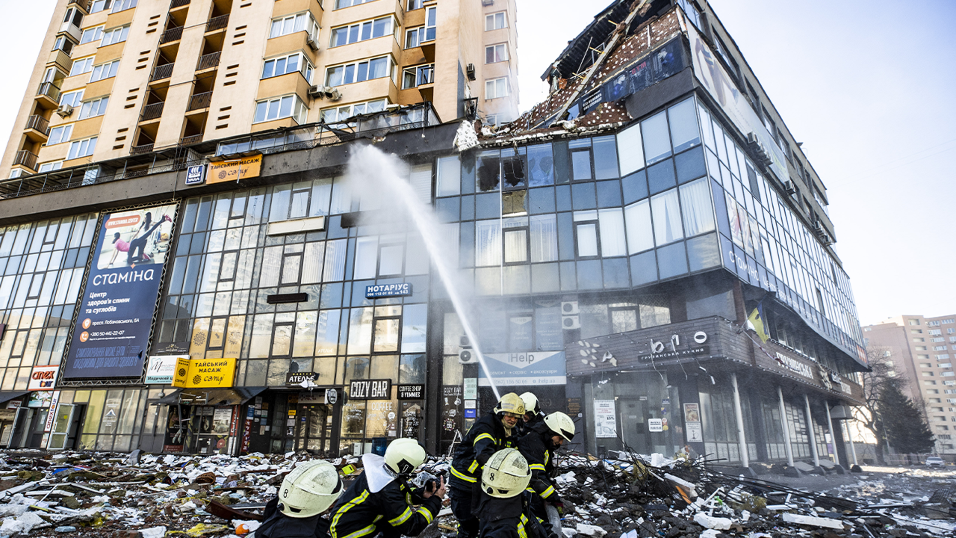 Firefighters work by a damaged apartment building in Kyiv which was hit by a recent shelling during Russia's invasion of Ukraine, on February 26, 2022