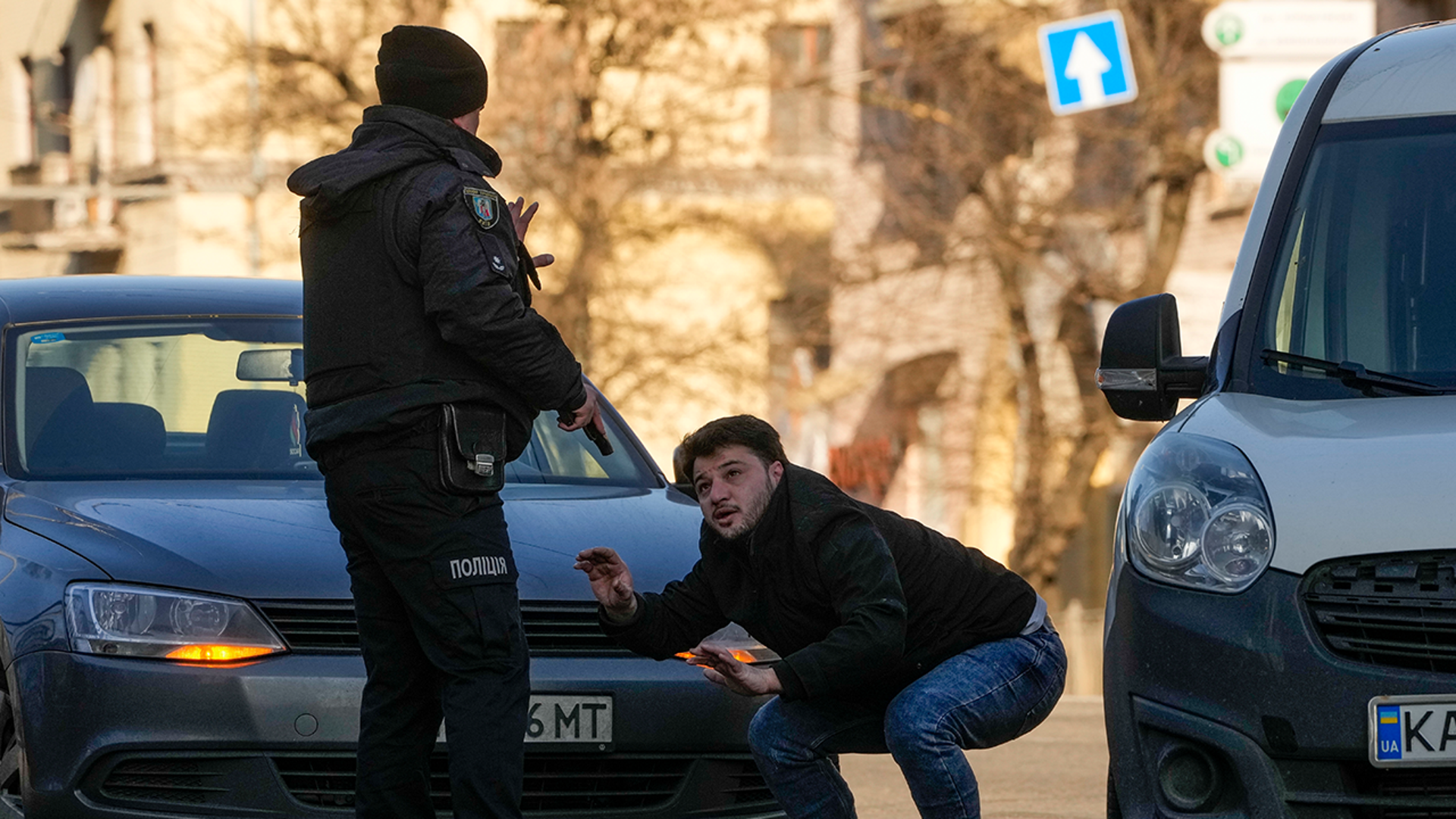 A Ukrainian police officer detains a car driver in a street in Kyiv, Ukraine, Saturday, Feb. 26, 2022. Russian troops stormed toward Ukraine's capital Saturday, and street fighting broke out as city officials urged residents to take shelter.