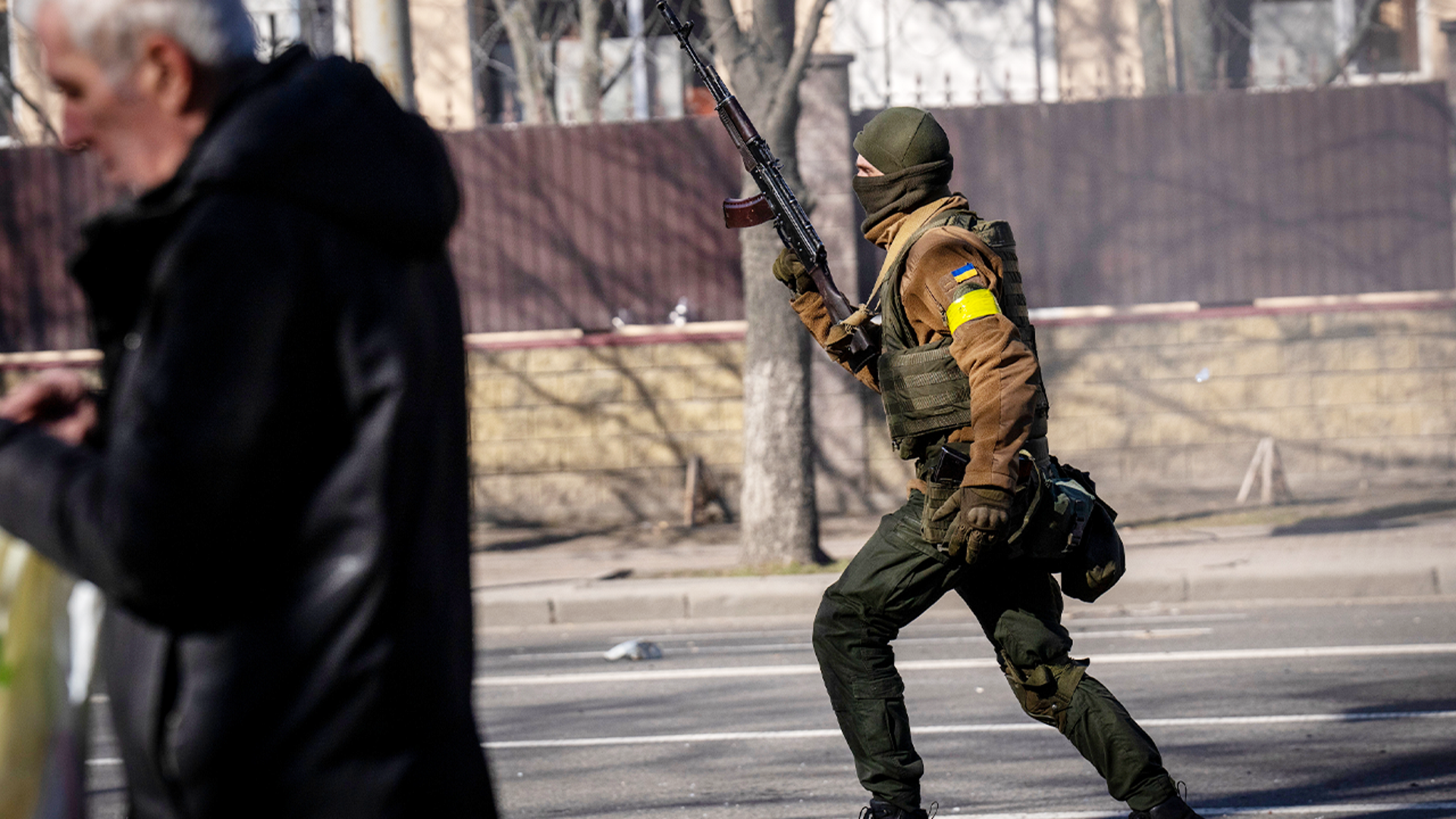 A Ukrainian soldier runs holding his weapon outside a military facility, in Kyiv, Ukraine, Saturday, Feb. 26, 2022. Russian troops stormed toward Ukraine's capital Saturday, and street fighting broke out as city officials urged residents to take shelter.