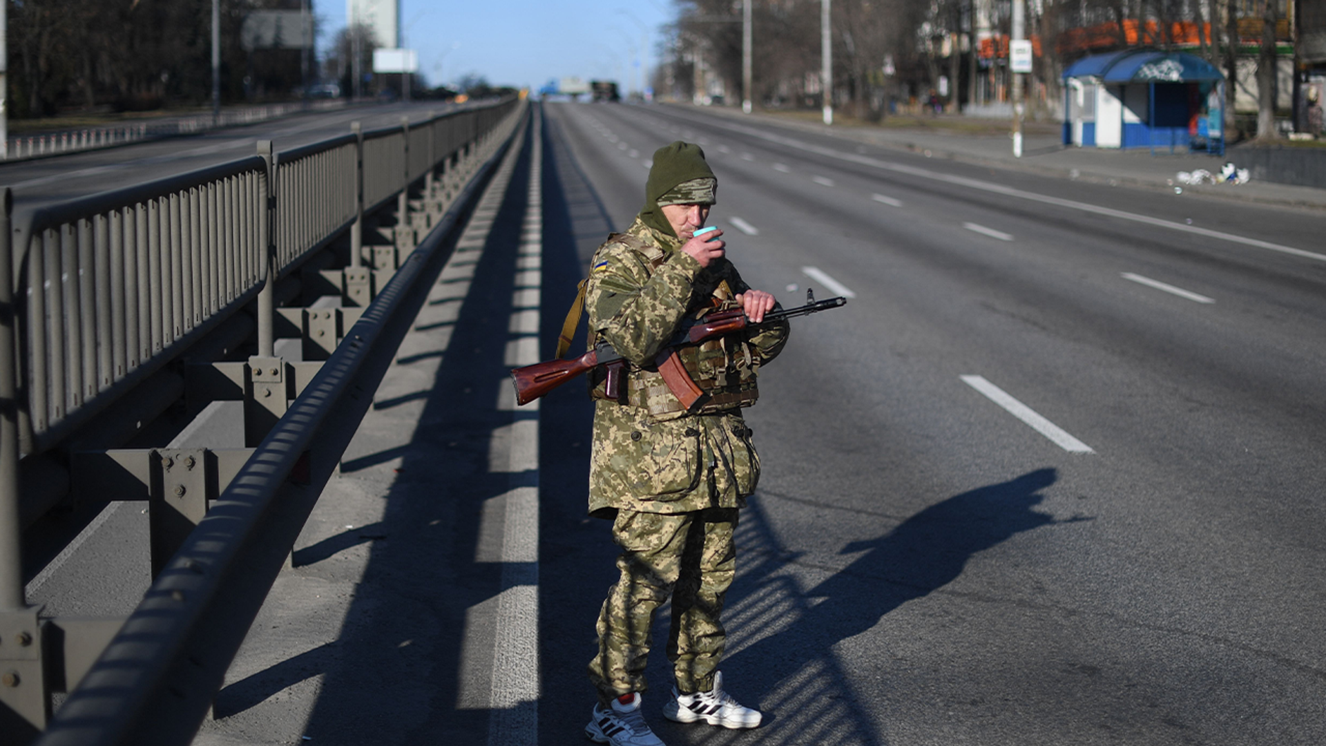 An Ukrainian service member drinks a cup of tea as he patrol the empty road on west side of the Ukrainian capital of Kyiv in the morning of February 26, 2022
