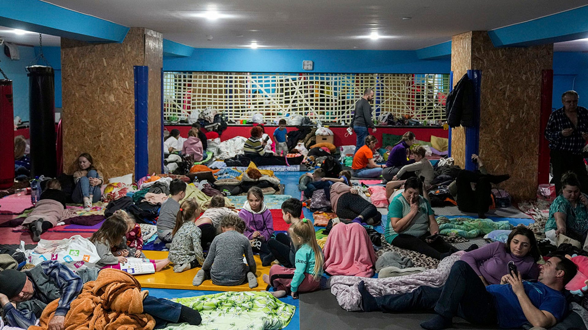 People sit and lie on the floor in the improvised bomb shelter in a sports center, which can accommodate up to 2000 people, in Mariupol, Ukraine, late Sunday, Feb. 27, 2022. Explosions and gunfire that have disrupted life since the invasion began last week appeared to subside around Kyiv overnight, as Ukrainian and Russian delegations prepared to meet Monday, Feb. 28, 2022 on Ukraine's border with Belarus. It's unclear what, if anything, those talks would yield. Terrified Ukrainian families huddled in shelters, basements or corridors, waiting to find out. (AP Photo/Evgeniy Maloletka)