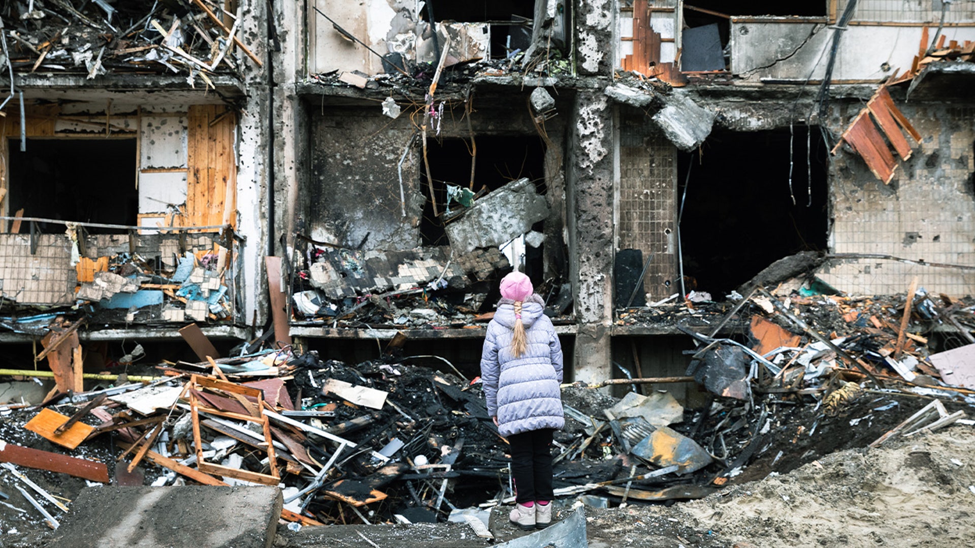 On 25 February 2022 in Kyiv, Ukraine, a girl looks at the crater left by an explosion in front of an apartment building which was heavily damaged during ongoing military operations.